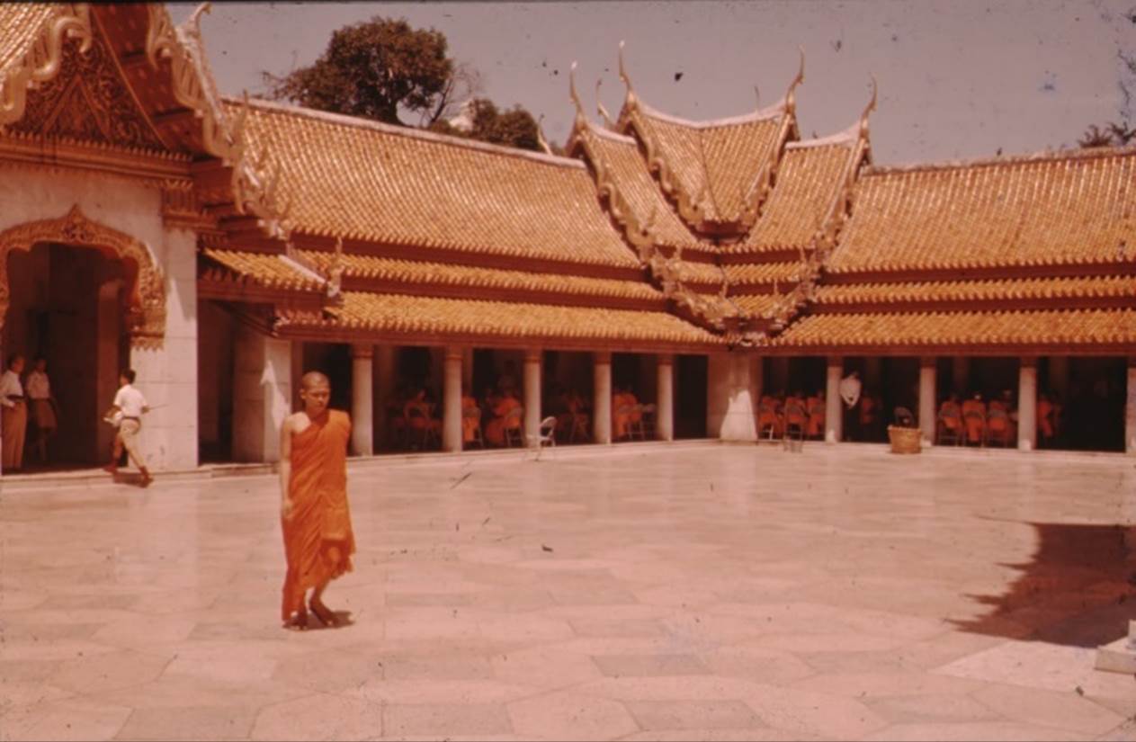 A person in an orange robe standing in front of a building
Description automatically generated with medium confidence